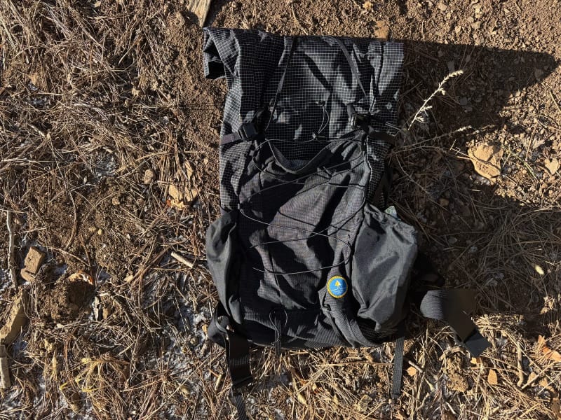 The Aspen Ultralight Backpack By Symbiosis Gear sitting on the ground in the woods during a big hike