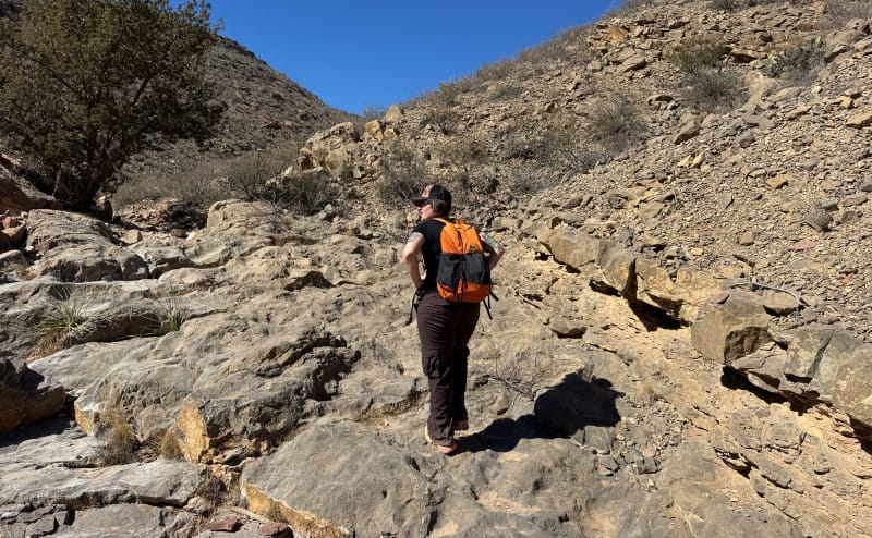 a woman wears the Wy'east Daypack By Six Moon Designs while hiking in the south west deserts and mountains