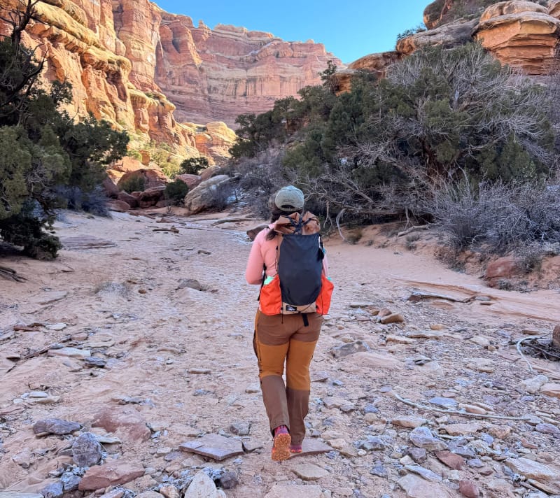 Hiker wearing an ultralight backpack walking through a red rock canyon in the desert Southwest.
