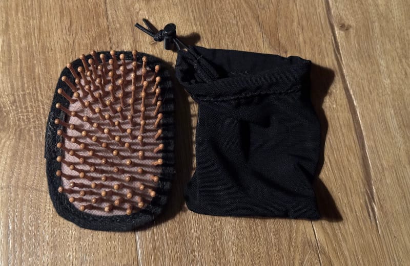 Compact hairbrush with wooden bristles and a black carrying pouch, designed for ultralight backpacking.