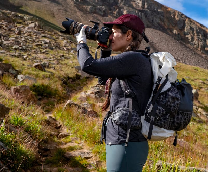 Backpacker wearing Hyperlite Mountain Gear Southwest backpack while photographing in a high alpine environment.