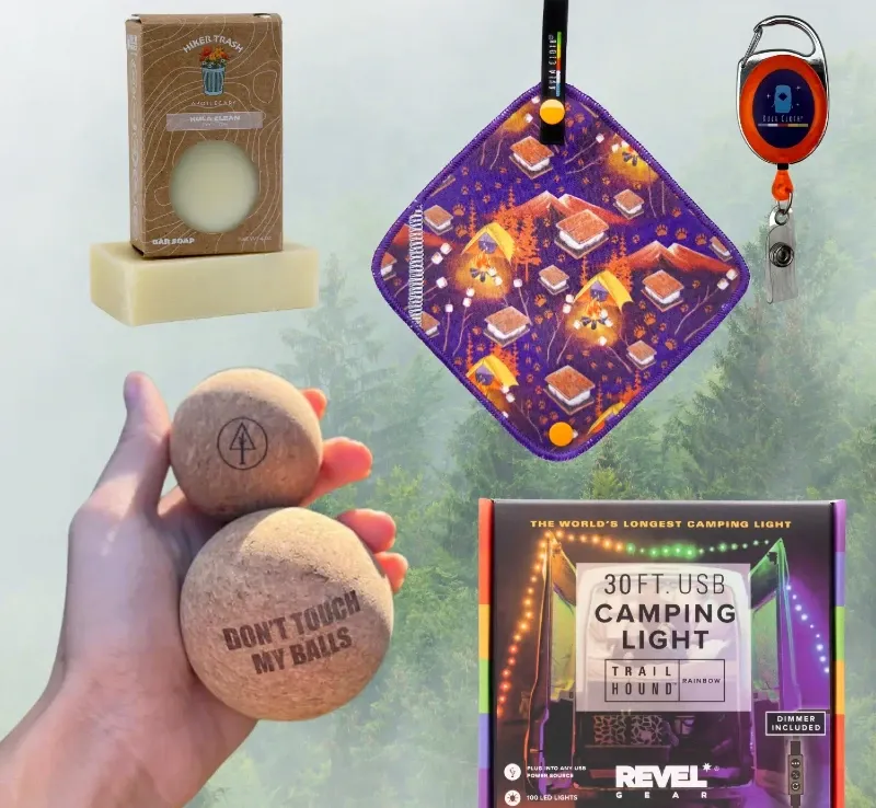 Alt Text: A selection of Kula Cloth products, including a Kula Cloth with a campsite design, a camping light, cork massage balls, and a bar of soap.
