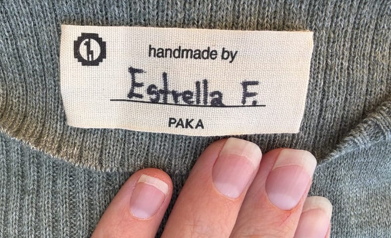 Close-up of a “Handmade by Estrella tag stitched into the bottom hem of the PAKA Ultralight COOLPLUS Crew
