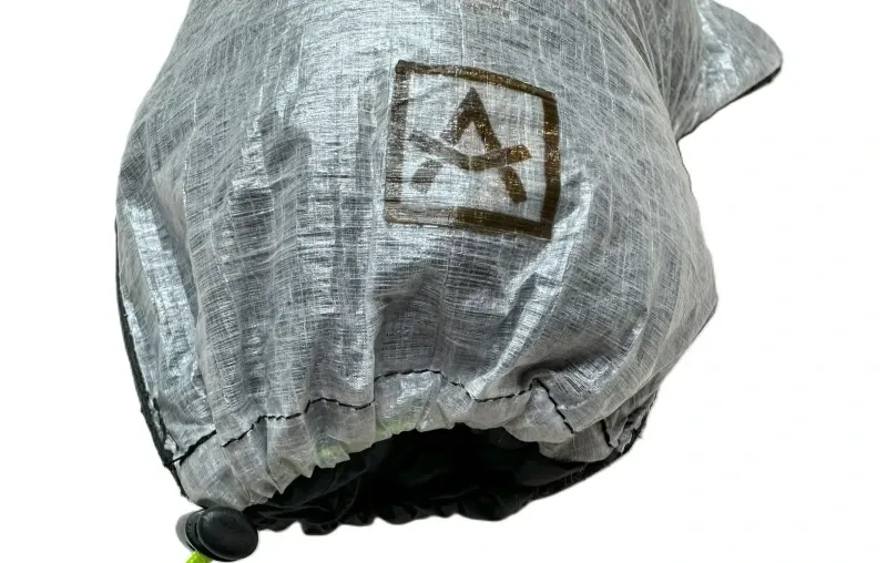 Single Adotec Gear Rain Mitt Stuff Sack resting on dry log with visible thumb design and drawcord