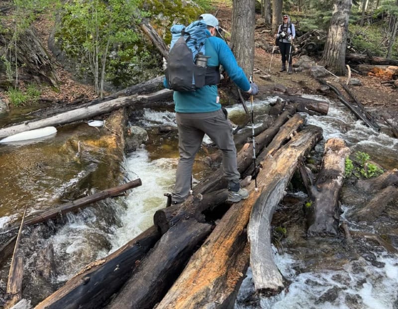 Hiker crossing a log bridge with the Exotic Pack Co FKP ultralight backpack in the Grand Canyon.