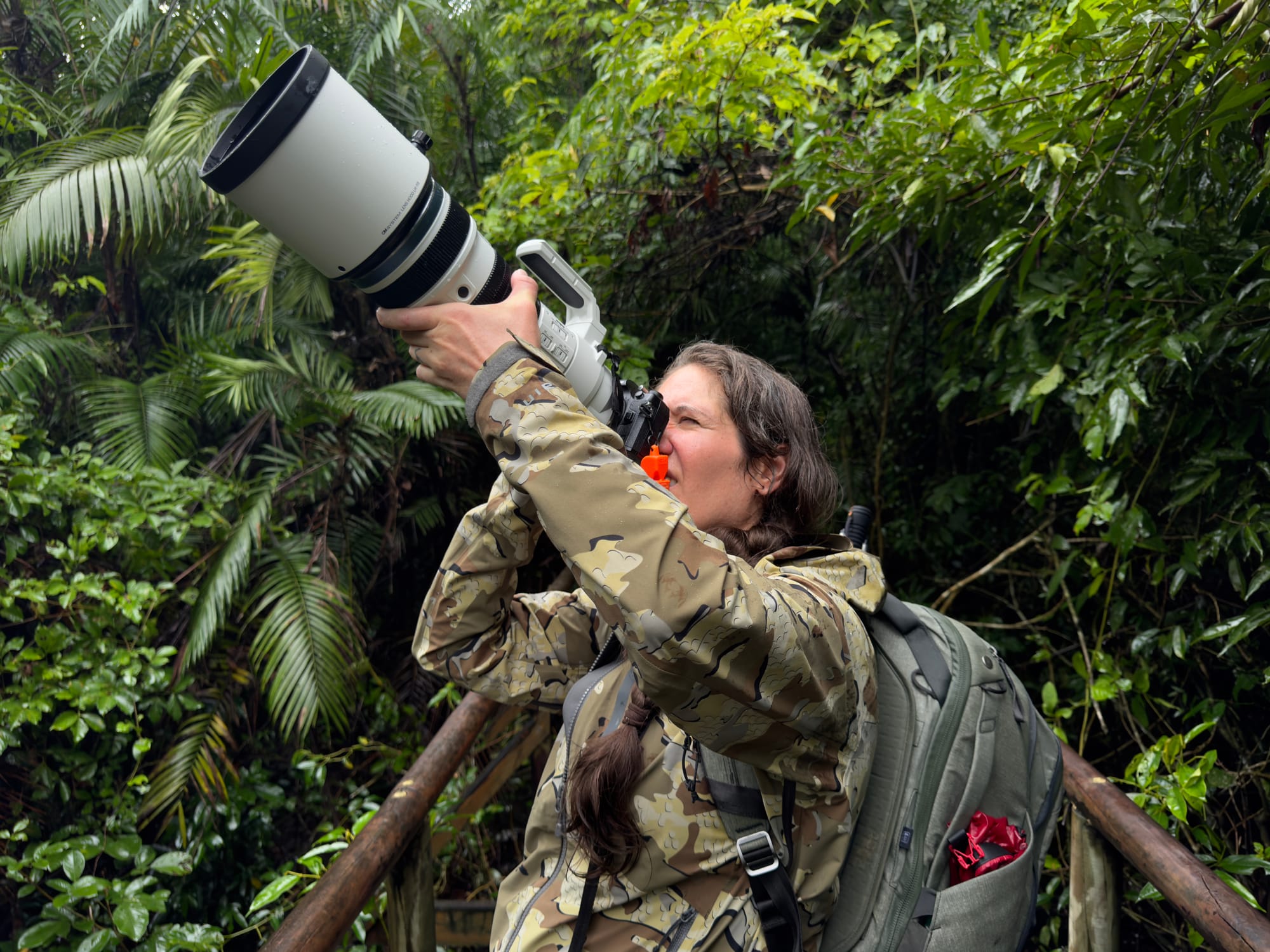 Photographer wearing KUIU Chugach TR Rain Jacket while using a long lens in a tropical rainforest.