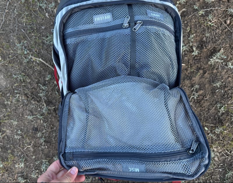  Interior mesh pocket system of the Dean 60 Backpack labeled for first aid, light, and miscellaneous gear.