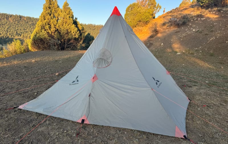  SlingFin Cinder Cone pyramid tent fully pitched in golden evening light on a hillside campsite.
