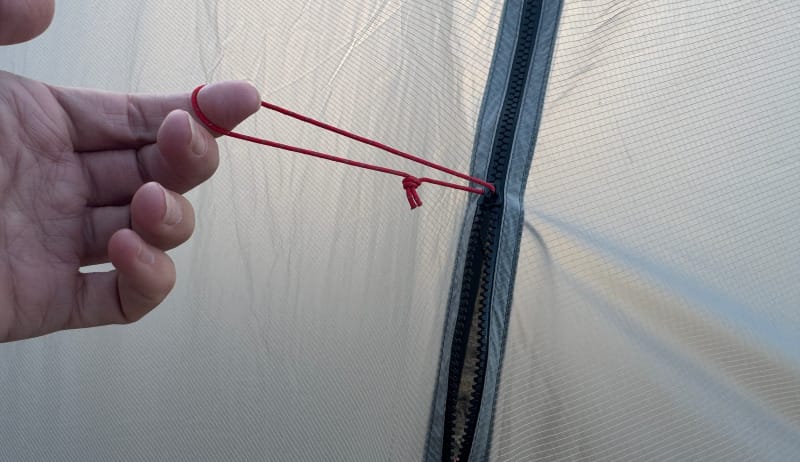  Close-up of hand holding internal guyline loop inside the SlingFin Cinder Cone tent showing setup detail.