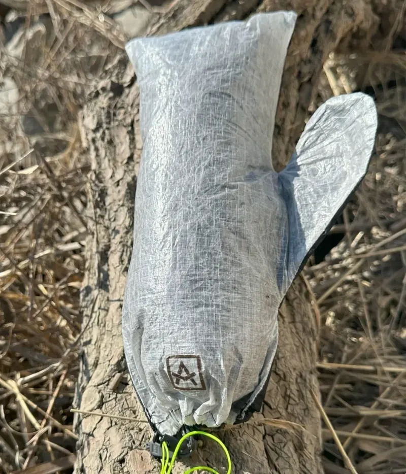 Detailed view of the Adotec waterproof mitt stuff sack showing logo and cinch cord in use