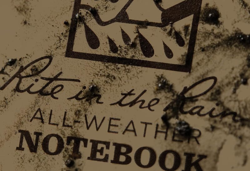 Close-up of a dirt-covered Rite in the Rain all-weather notebook showing its water-resistant durability.