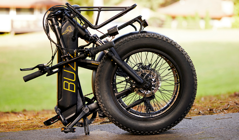  Buzz Centris Folding eBike shown folded down with fat tires and compact storage configuration on pavement.