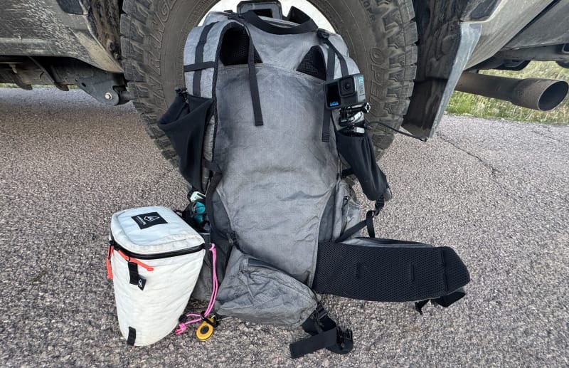  Durston Kakwa 55 backpack fully packed, resting against a truck, with accessories like a Hyperlite Camera Pod and water bottle.