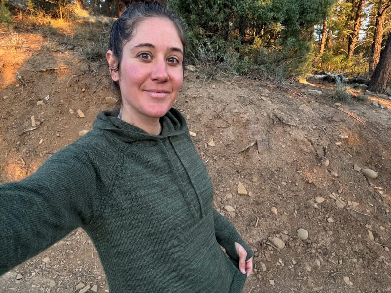 Close-up selfie of woman wearing the PAKA Women’s Hoodie in a forest setting.