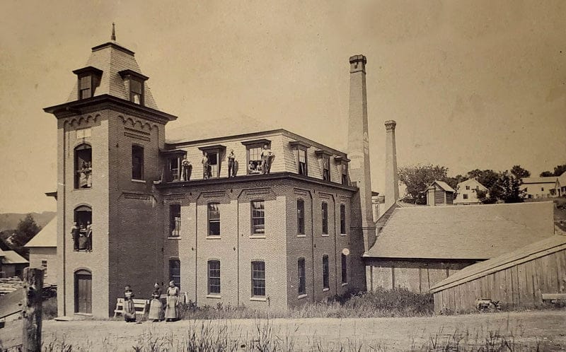 Historic photograph of the L.W. Packard wool mill building in New Hampshire, showing workers and early textile production roots of Minus33.