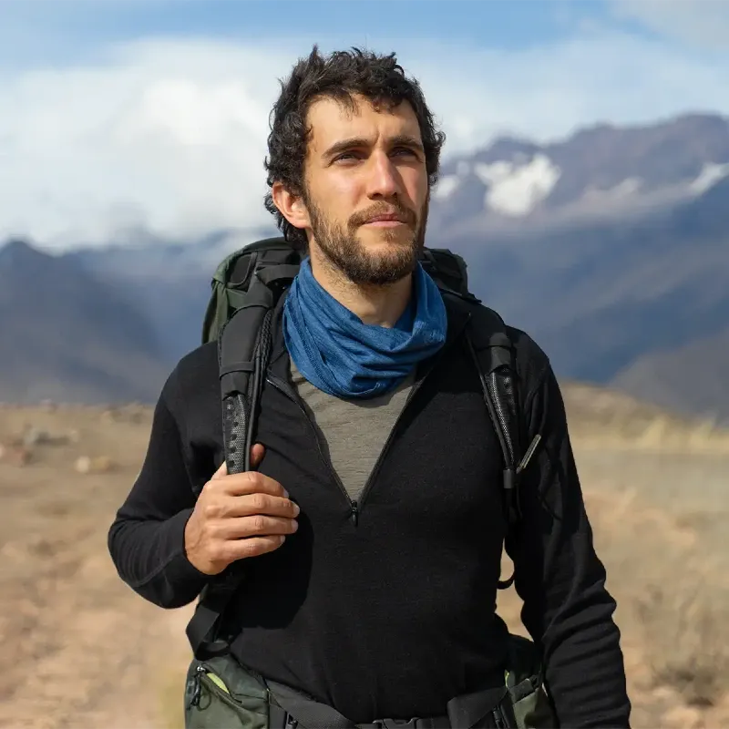 Hiker wearing Arms of Andes Alpaca Wool Half-Zip under a shell jacket during cold-weather trekking, illustrating layering performance and warmth.