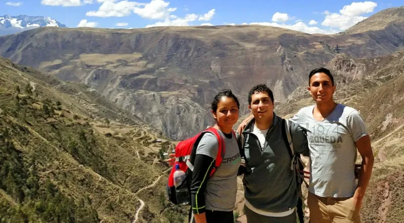 Three members of the Arms of Andes team smiling on a mountain trail in the Peruvian Andes, symbolizing the brand’s local heritage and sustainability.