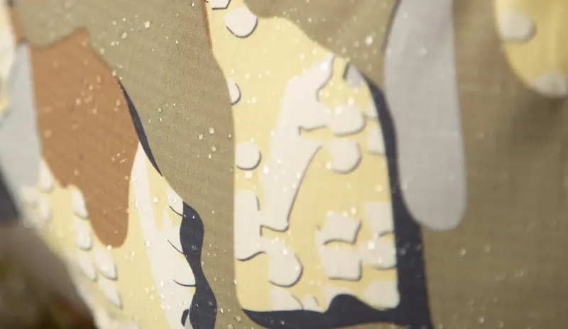 Close-up of KUIU Kenai Hooded Jacket camouflage fabric showing water-repellent DWR beading on the surface.