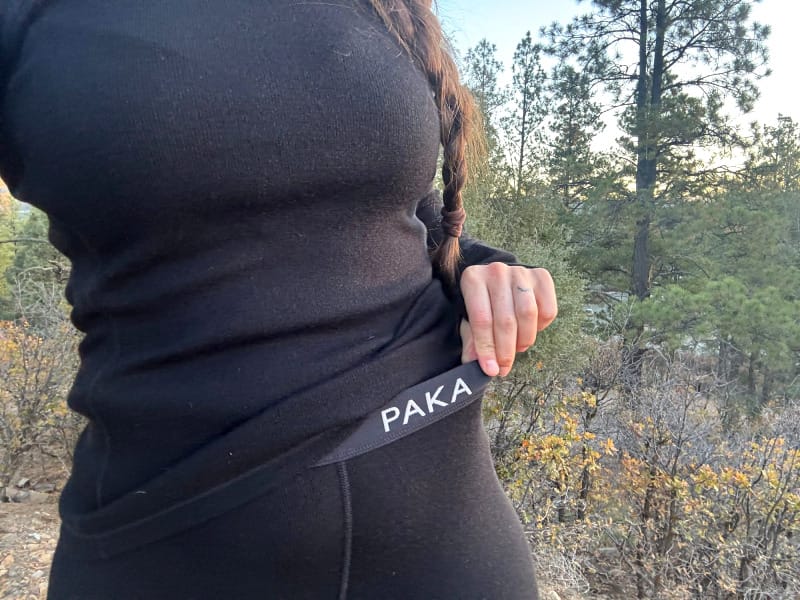 Close-up of PAKA Thermal Pants waistband and logo on black alpaca base layer, highlighting secure and flexible fit for outdoor use.