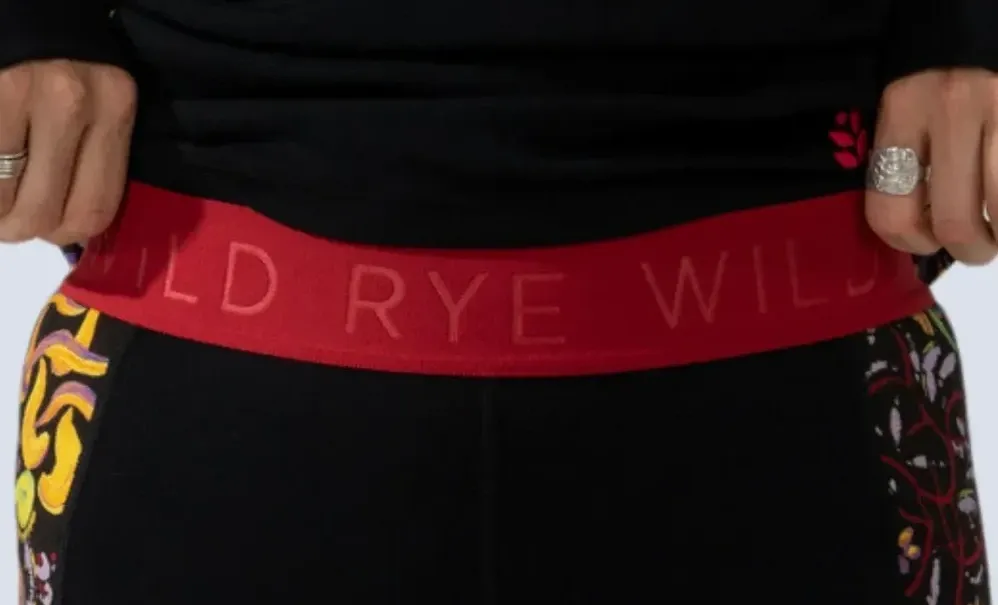 Close-up of Wild Rye Bassett leggings waistband showing the red Wild Rye logo band and floral side panels.