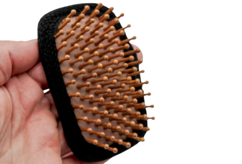stock image of hiker hairbrush by chicken tramper ultralight gear being held with a hand and white background
