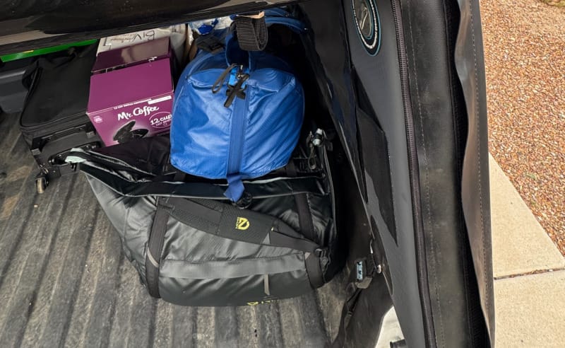 A packed truck bed with outdoor gear, featuring the NEMO Equipment Double Haul Convertible Duffel & Tote in use, shown loaded with luggage and adventure equipment.
