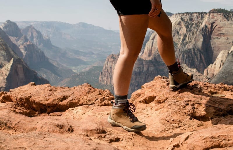 traveler walking across a desert overlook with hiking boots in a wide open national park landscape.