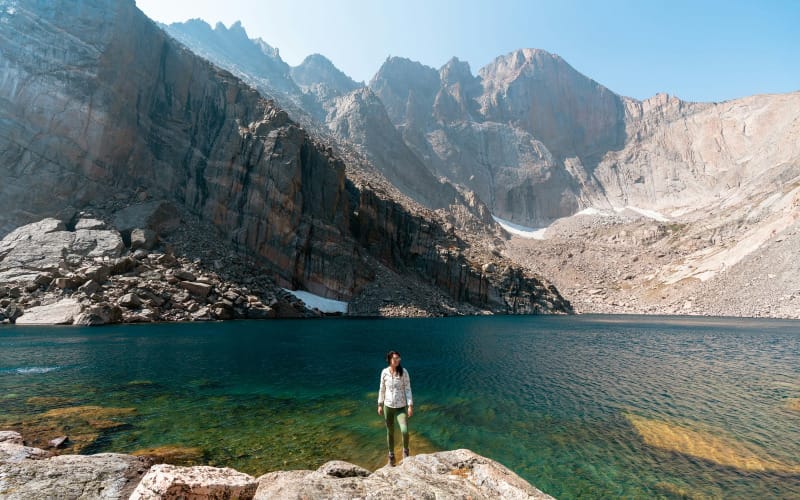 a hiker stands at chasm lake in rocky mountain national park with her gift from 2025 of a hoodie