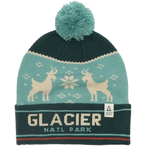 Knitted Glacier National Park beanie with mountain goat designs and a pom-pom on top in teal and dark green colors.