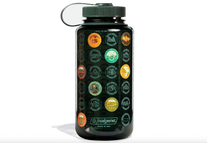 Dark green Nalgene water bottle covered in circular national park emblem stickers representing different U.S. national parks.
