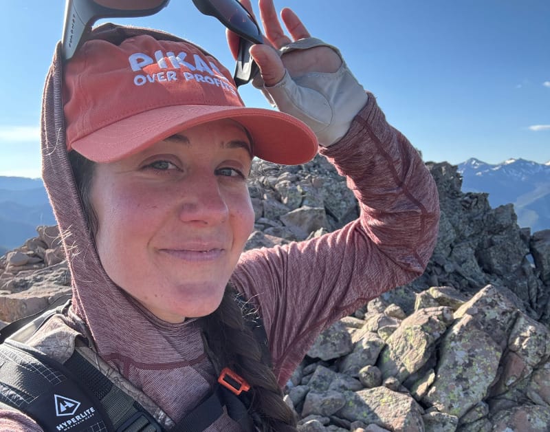 hiker on a mountain summit in a wool sun shirt