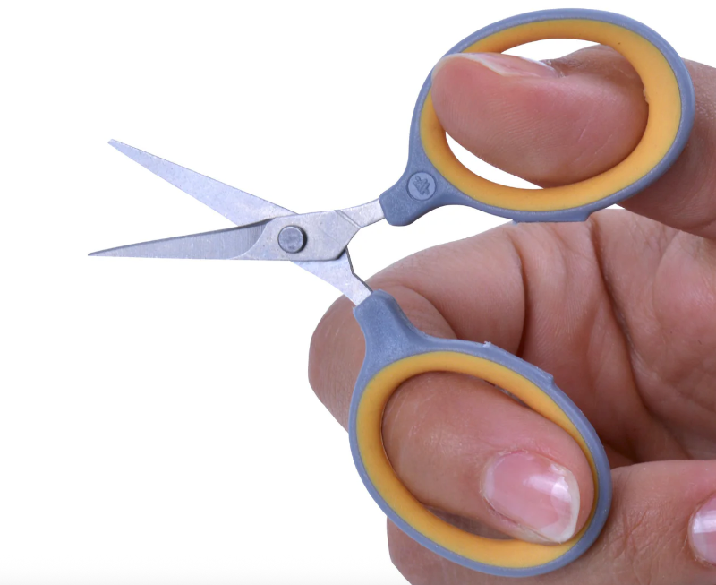 a hand using titanium ultralight scissors with a blank background