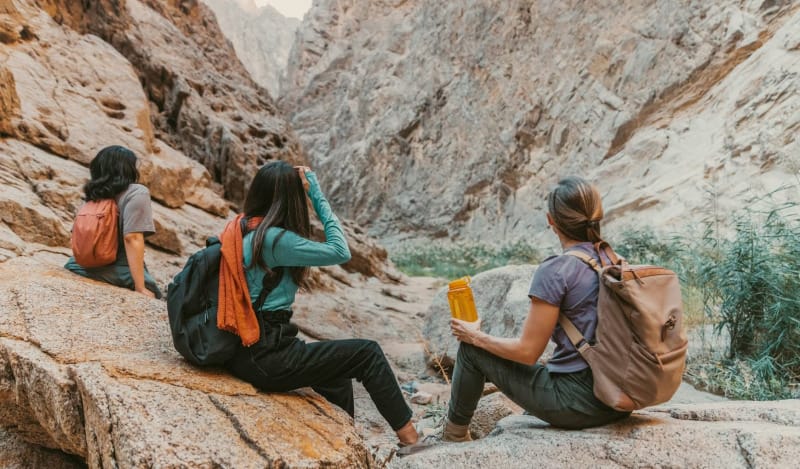 Woman hiking with a backpack on a desert trail using gear from women-led outdoor brands.