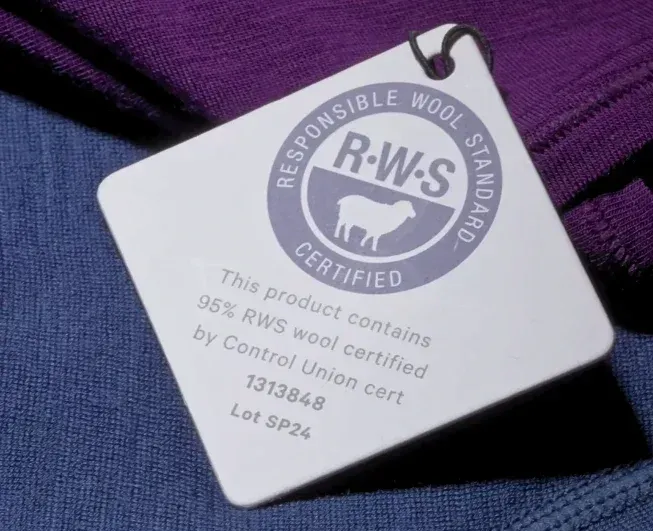 Close-up of a Woolly Clothing tag showing Responsible Wool Standard certification on merino fabric.
