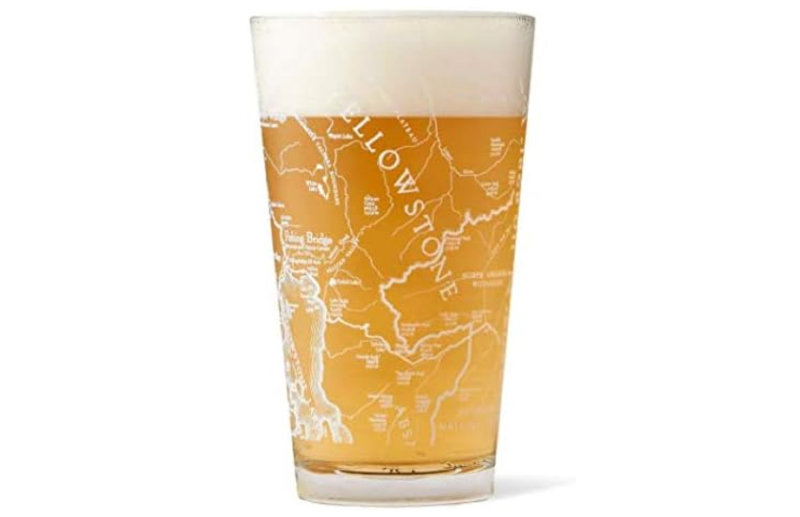 Clear pint glass filled with beer, featuring an etched map of Yellowstone National Park including major landmarks and trails.