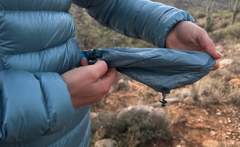 a hiker showing the stuff sack of the accelerator down jacket by himali in the southwest desert