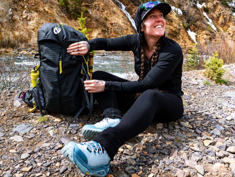 a backpackers sitting near a river in the mountains wearing branwyn's compression leggings in black