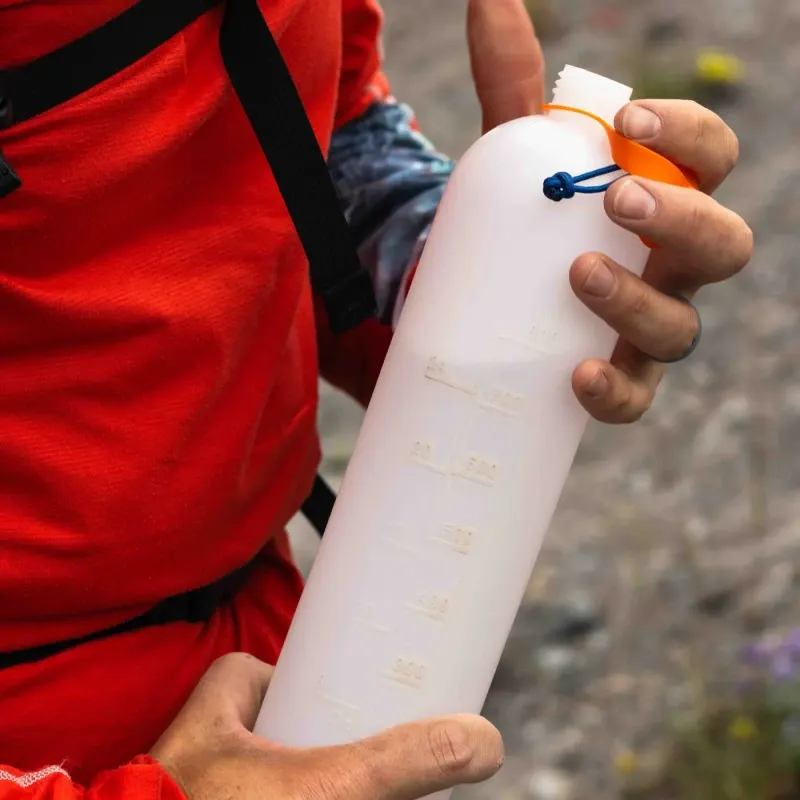 Hand holding a CNOC ThruBottle showing the raised measurement lines on the side.
