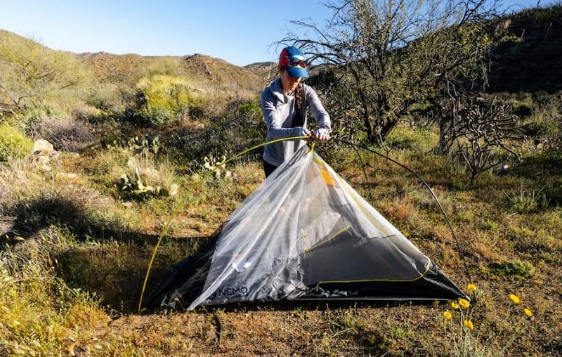 an ultralight backpacker pitching a semi-freestanding tent in the sonoran desert