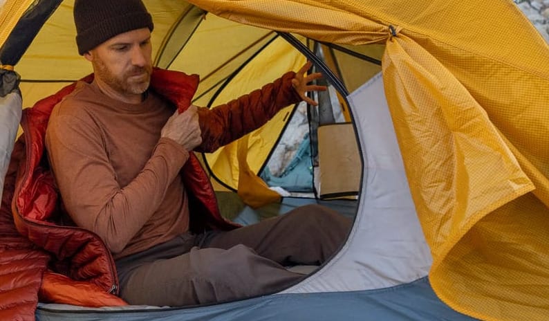 Solo backpacker sitting inside an ultralight backpacking tent at camp, showing interior space and comfort after a day on the trail