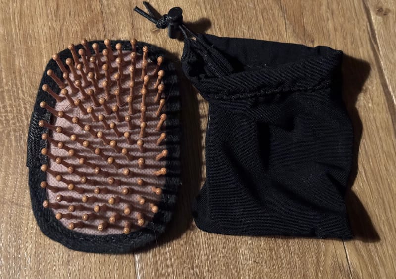 Ultralight hairbrush by Chicken Tramper Ultralight Gear with a lightweight storage pouch, designed for minimalist backpacking kits.