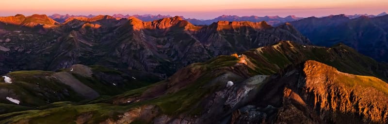 Dramatic mountain ridgelines at sunrise with warm light illuminating alpine terrain