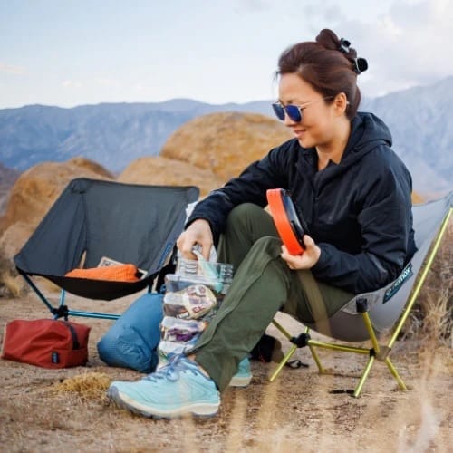 Backpacker accessing food from a Grubcan Wave bear canister at camp during a backpacking trip