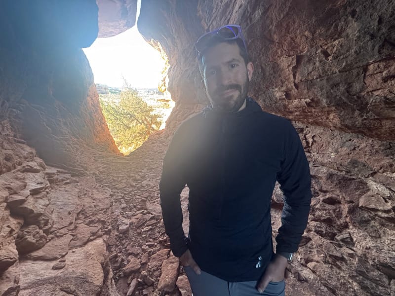 man wearing Outdoor Vitals Pursuit Hybrid Fleece standing in rocky cave opening in desert environment