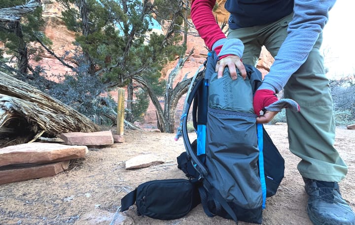 an ultralight backpacker takes a gossamer gear tent out of his gossamer gear backpack at his backcountry camp site
