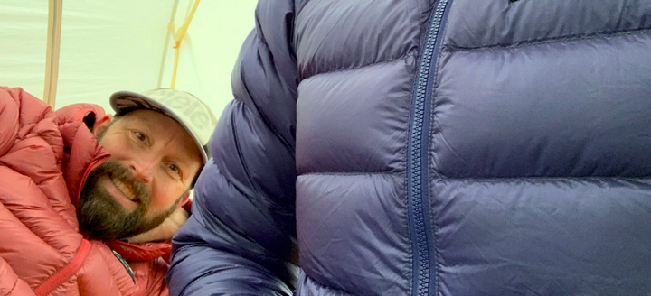 two people wearing one of the best down jackets of 2025 in a tent to stay warm!