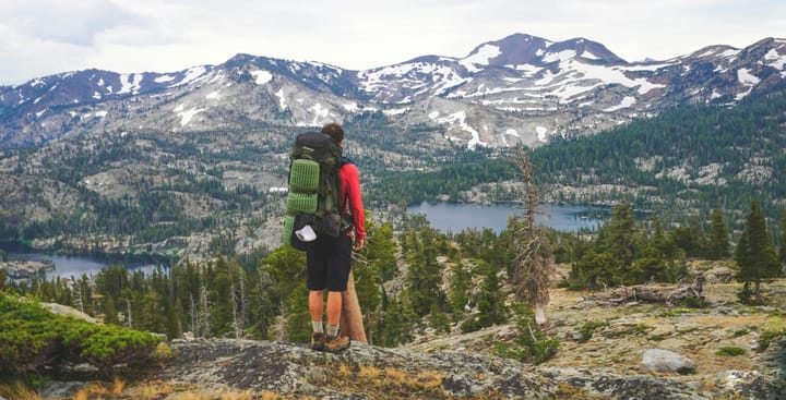 a hiker in a vast mountain landscape wearing a backpack and one of the top picks for best hiking socks of 2025