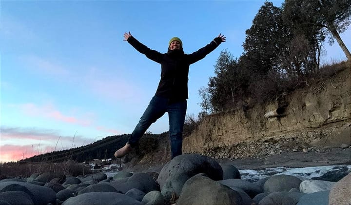 a woman wears the apu pakafill parka by paka on a frigid morning out along a river