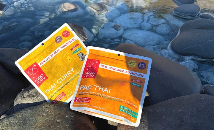 two good to-go dehydrated meals laid out near a creek on a backpacking trip