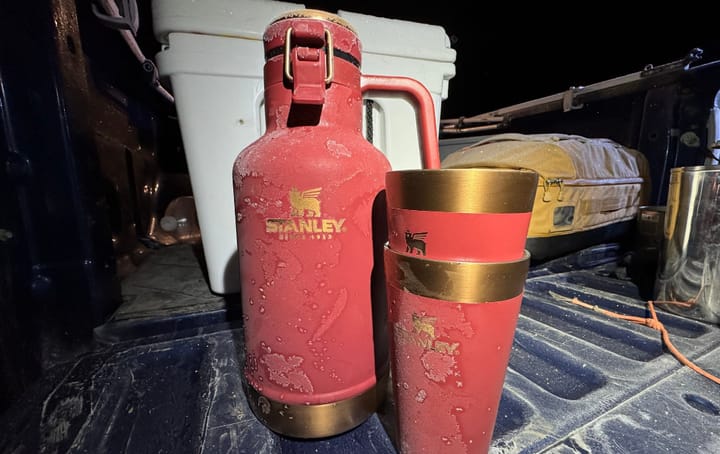 Classic Easy-Pour Growler 64oz By Stanley sitting on the tailgate of a truck in freezing cold conditions during a road trip
